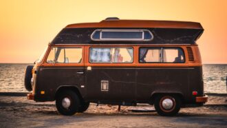 An old style campervan with the sun setting in the background